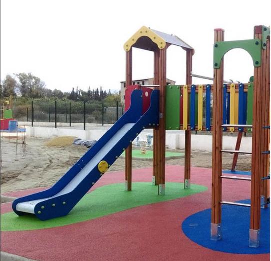 Parque infantil de úso público contiene una pasarela, trepador y tobogán.