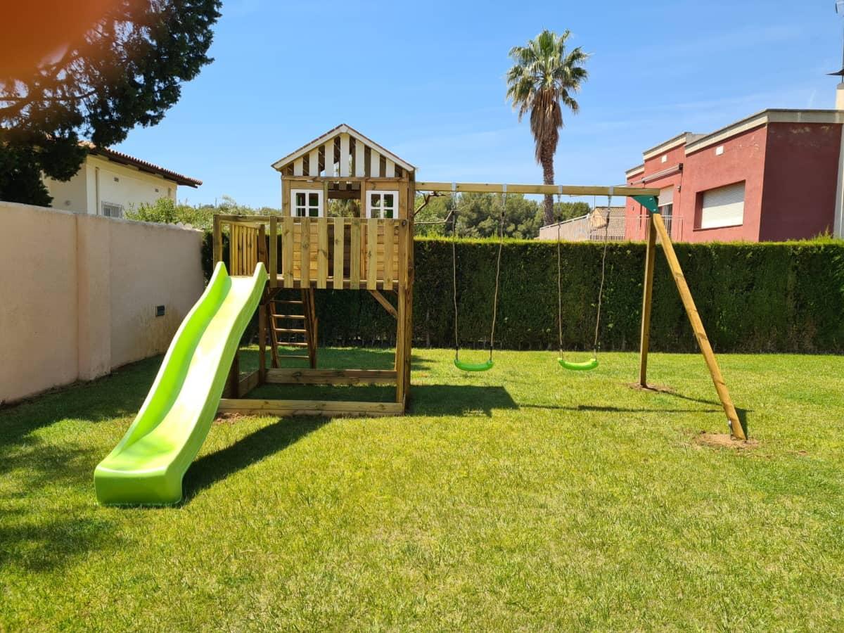 Parc infantil format per una caseta Lollipop XL posada a una plataforma amb escala, paret d'escalada i rampa de tobogan. Aquesta versió a més a més té un gronxador.