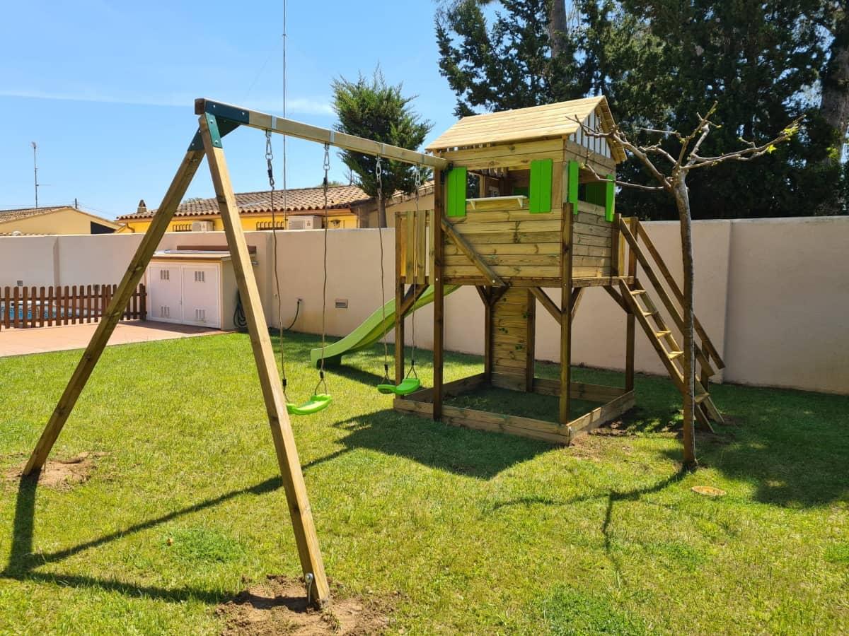 Parc infantil format per una caseta Lollipop XL posada a una plataforma amb escala, paret d'escalada i rampa de tobogan. Aquesta versió a més a més té un gronxador.